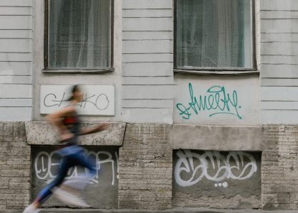 Blurred motion of a woman running past a graffiti-covered urban wall. Captures dynamic energy.