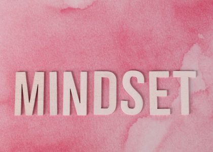 Wooden letters spelling 'MINDSET' on a textured pink background, symbolizing motivation.